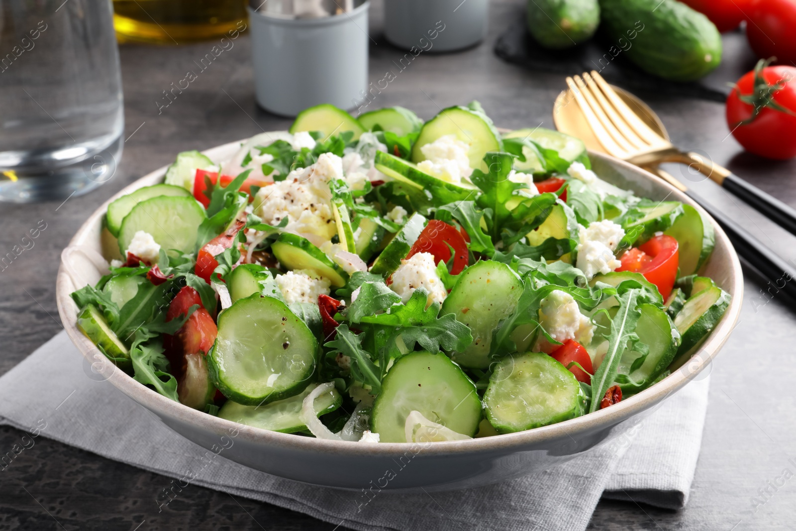 Photo of Plate of delicious cucumber salad served on grey table, closeup