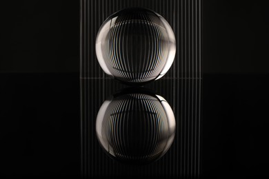 Transparent glass ball on black mirror surface