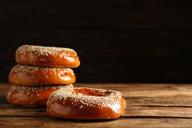 Photo of Delicious fresh bagels with sesame seeds on wooden table, space for text