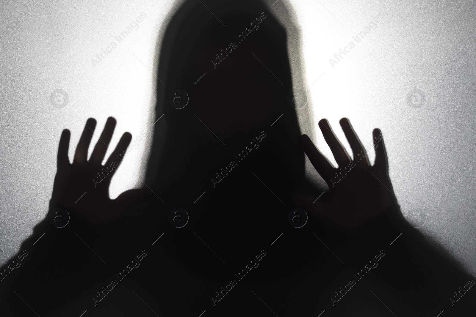 Photo of Silhouette of ghost behind glass against grey background