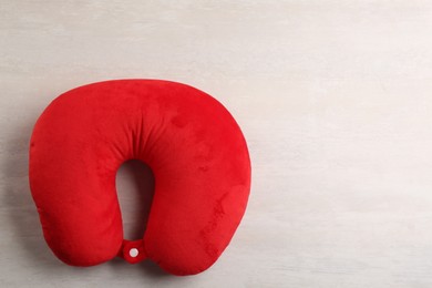 Red travel pillow on light background, top view. Space for text