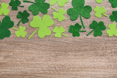 Decorative clover leaves on grey wooden table, flat lay with space for text. Saint Patrick's Day celebration