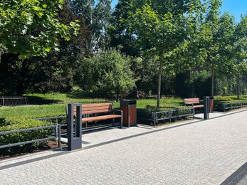 Beautiful walkway with wooden benches in park on sunny day