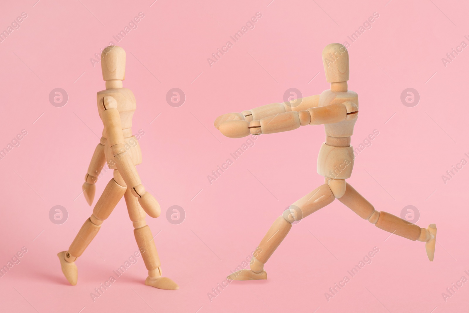 Image of Wooden human models in different poses on pink background