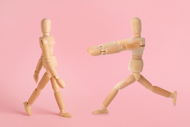 Image of Wooden human models in different poses on pink background