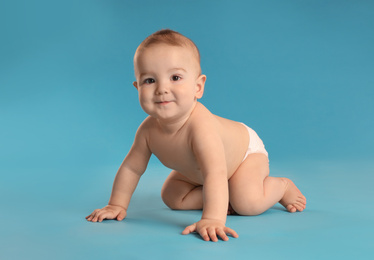 Photo of Cute little baby in diaper on light blue background