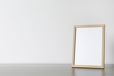 Empty square frame on wooden table, space for text