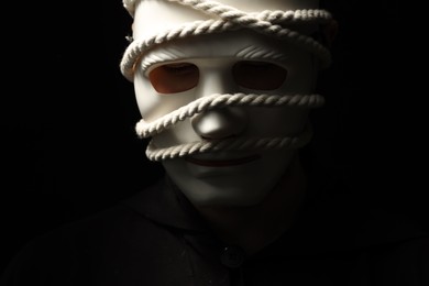 Photo of Theatrical performance. Man with plastic mask and hemp rope on black background