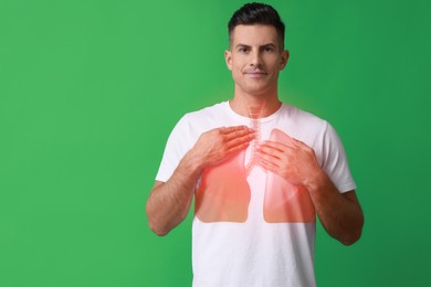 Handsome man holding hands near chest with illustration of lungs on green background. Space for text