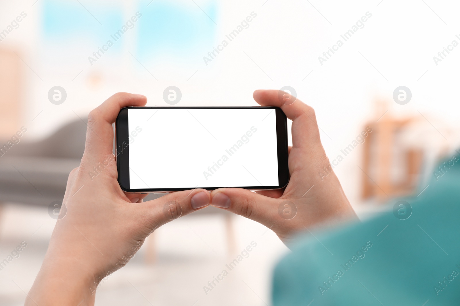 Photo of Man holding smartphone with blank screen indoors, closeup of hands. Space for text