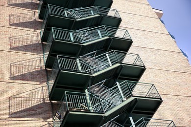 Photo of Modern metal empty fire escape ladder near building outdoors, low angle view