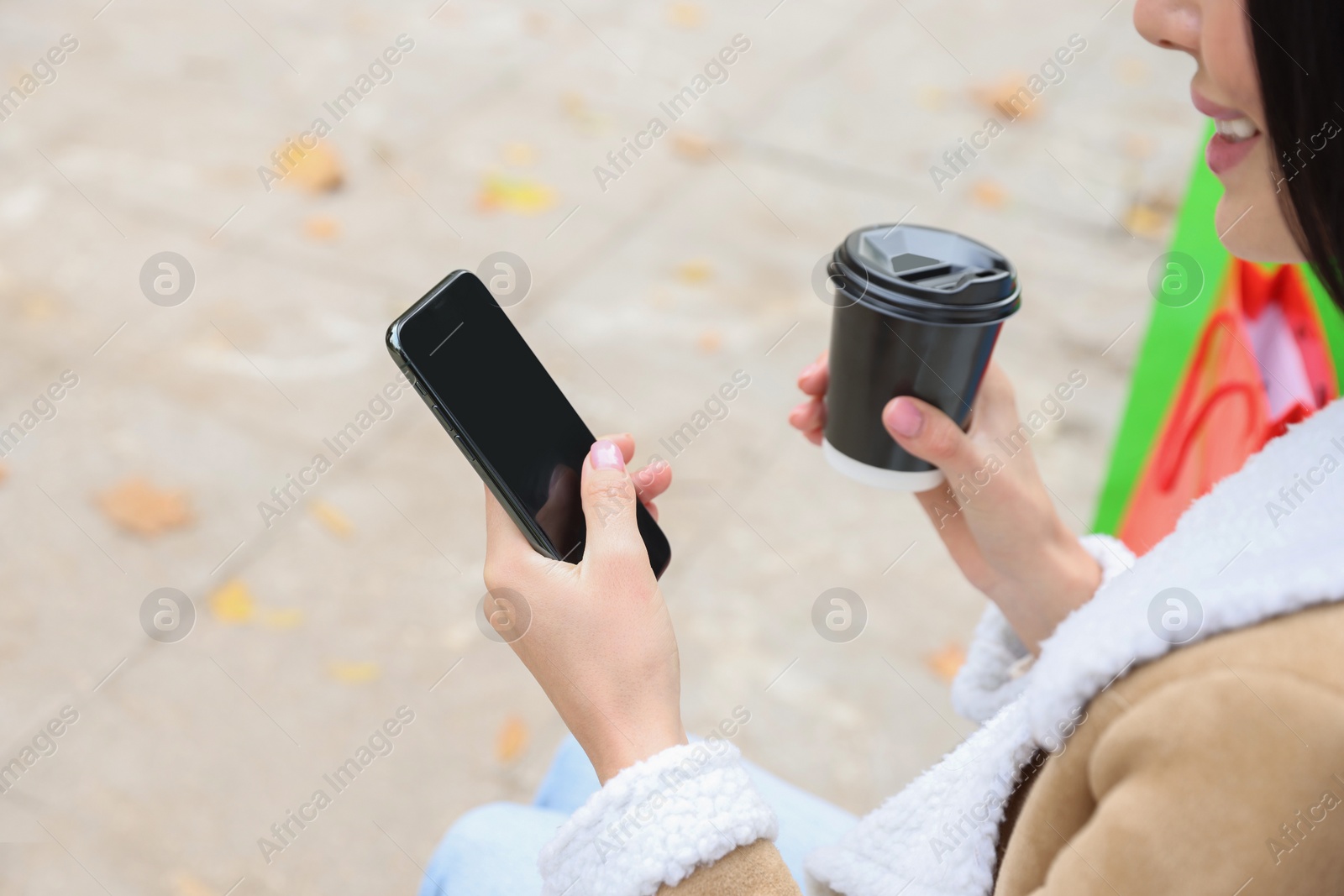 Photo of Special Promotion. Young woman with smartphone and cup of drink outdoors, closeup