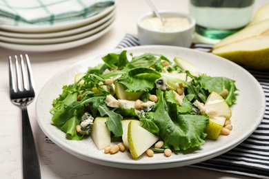 Photo of Tasty salad with pear slices, lettuce and pine nuts on table, closeup