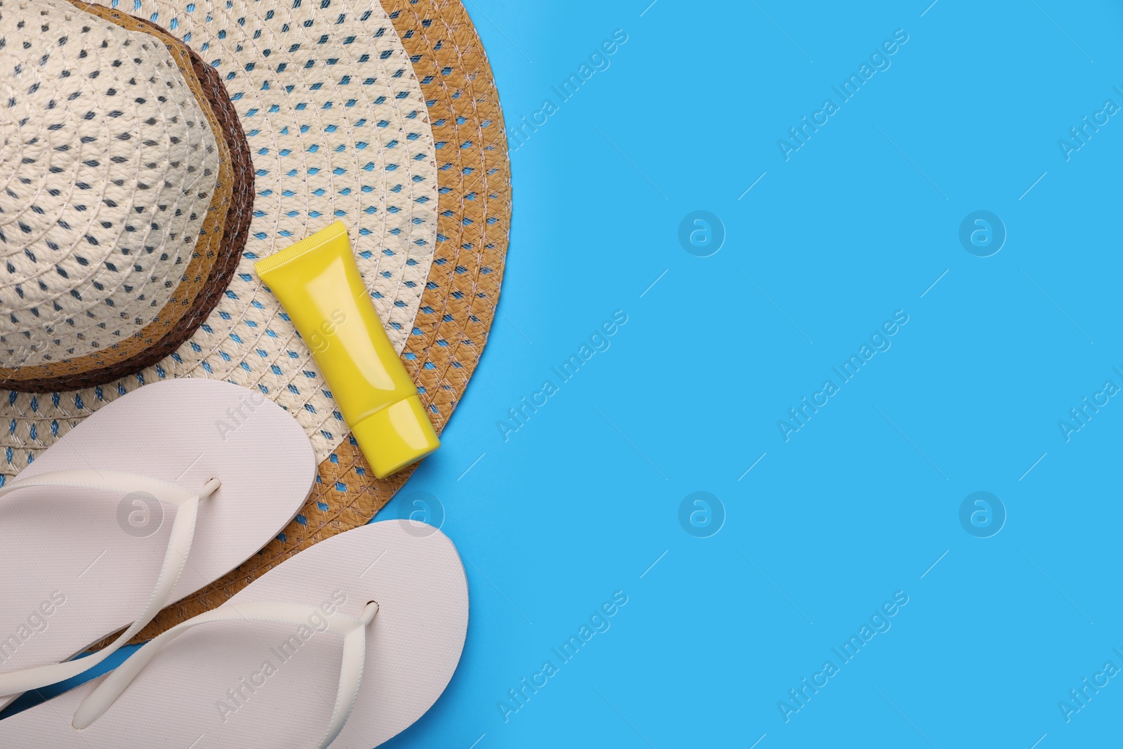 Straw hat, sunscreen and flip flops on light blue background, flat lay and space for text. Beach accessories Photo of Straw hat, sunscreen and flip flops on light blue background, flat lay and space for text. Beach accessories