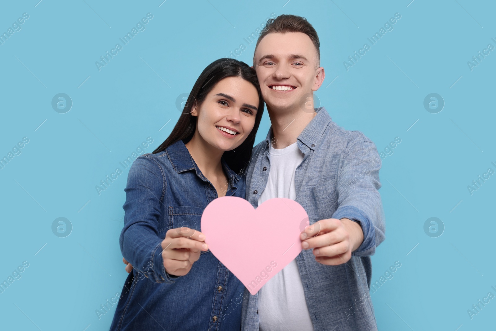 Photo of Lovely couple with decorative heart on light blue background. Valentine's day celebration