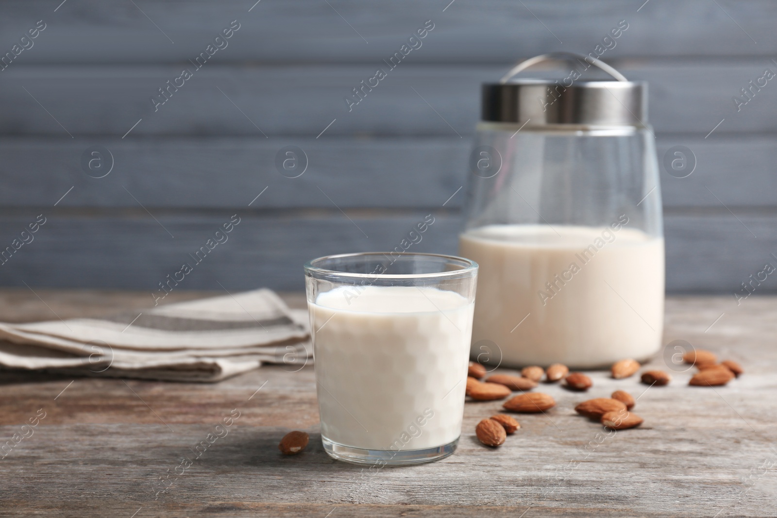 Photo of Glass with almond milk and nuts on wooden table