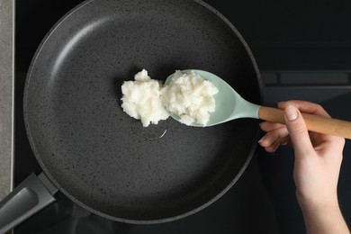 Woman cooking with coconut oil on induction stove, top view