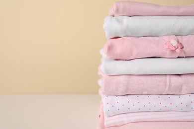 Photo of Stack of baby girl's clothes on white table, closeup. Space for text