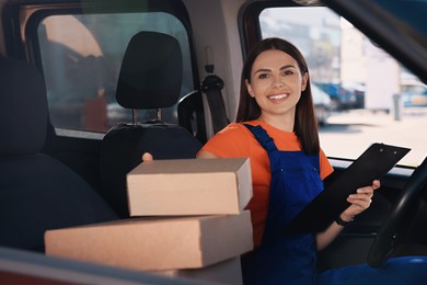 Courier with clipboard checking packages in car