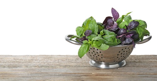 Photo of Metal colander with fresh basil leaves on wooden table against white background. Space for text