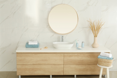 Round mirror over vessel sink in stylish bathroom interior