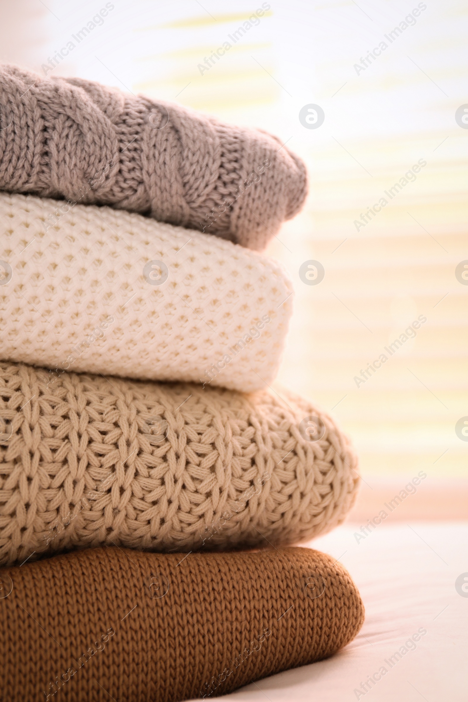 Photo of Stack of folded warm sweaters on bed indoors, closeup
