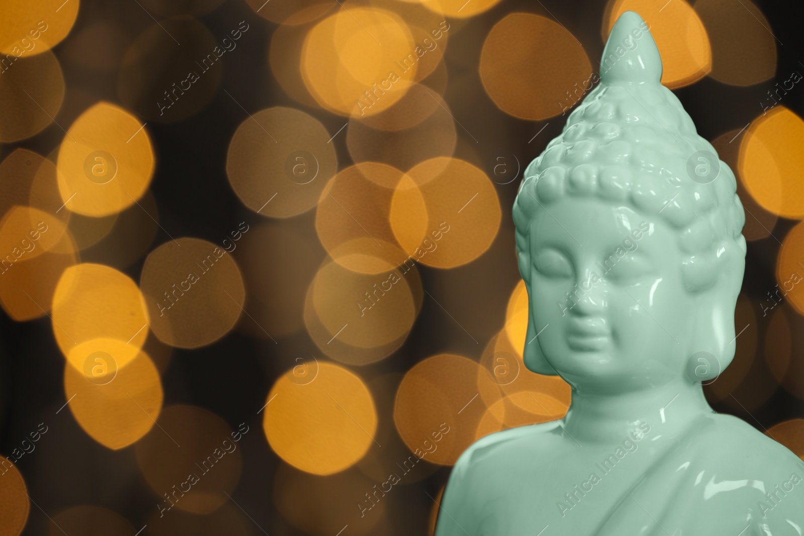 Photo of Buddha statue against blurred lights, closeup. Space for text