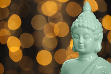 Photo of Buddha statue against blurred lights, closeup. Space for text