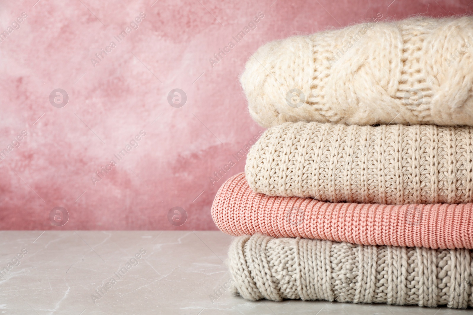 Photo of Stack of folded knitted sweaters on table. Space for text