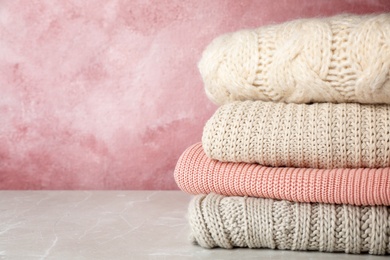 Photo of Stack of folded knitted sweaters on table. Space for text