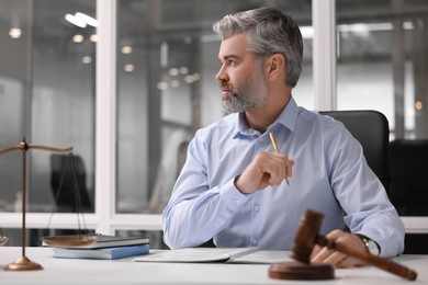 Serious lawyer at table in office, space for text