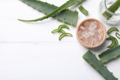 Photo of Aloe vera gel and slices of plant on white wooden table, flat lay. Space for text