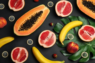 Photo of Flat lay composition with condoms and exotic fruits on black background. Erotic concept