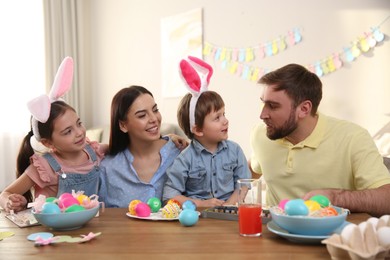 Photo of Happy family painting Easter eggs at table indoors