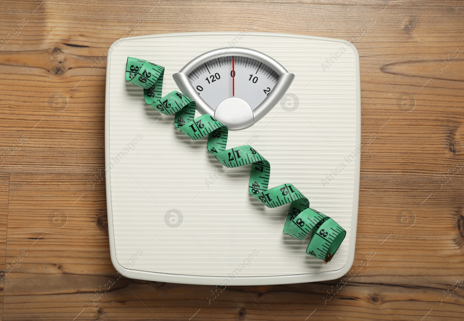 Photo of Scales and measuring tape on wooden floor, top view