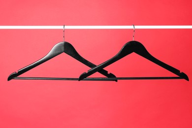 Photo of Empty black clothes hangers on metal rail against color background