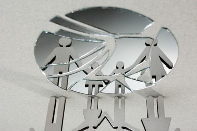 Human figures reflected in broken mirror on gray background. Divorce concept