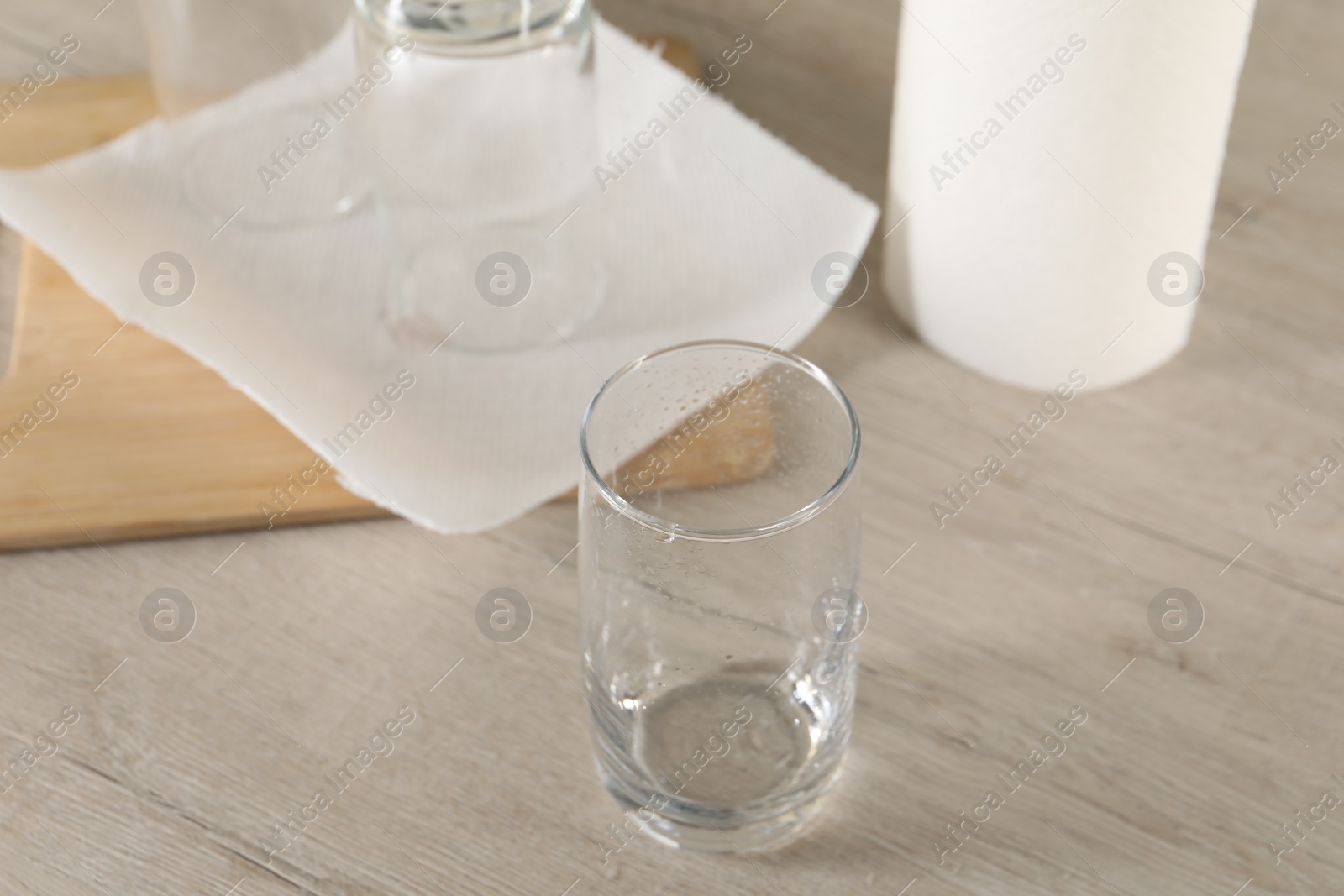 Photo of Clean glasses and paper towels on light wooden table