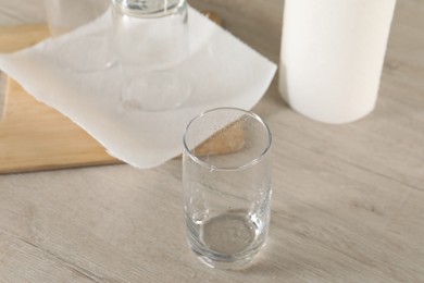 Photo of Clean glasses and paper towels on light wooden table