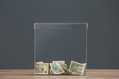 Donation box with money on table against grey background