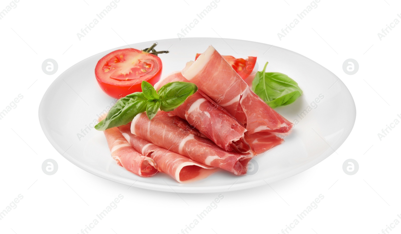 Photo of Plate with rolled slices of delicious jamon, cut tomato and basil isolated on white