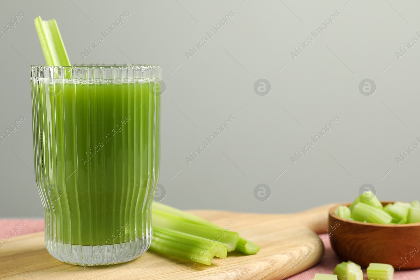 Photo of Glass of delicious celery juice and vegetables on wooden board, closeup. Space for text