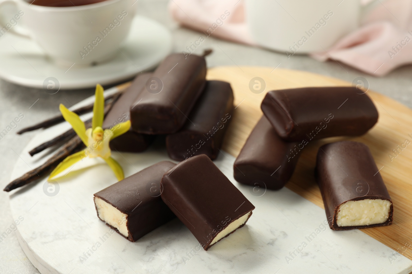 Photo of Glazed curd cheese bars, vanilla pods and flower on table, closeup