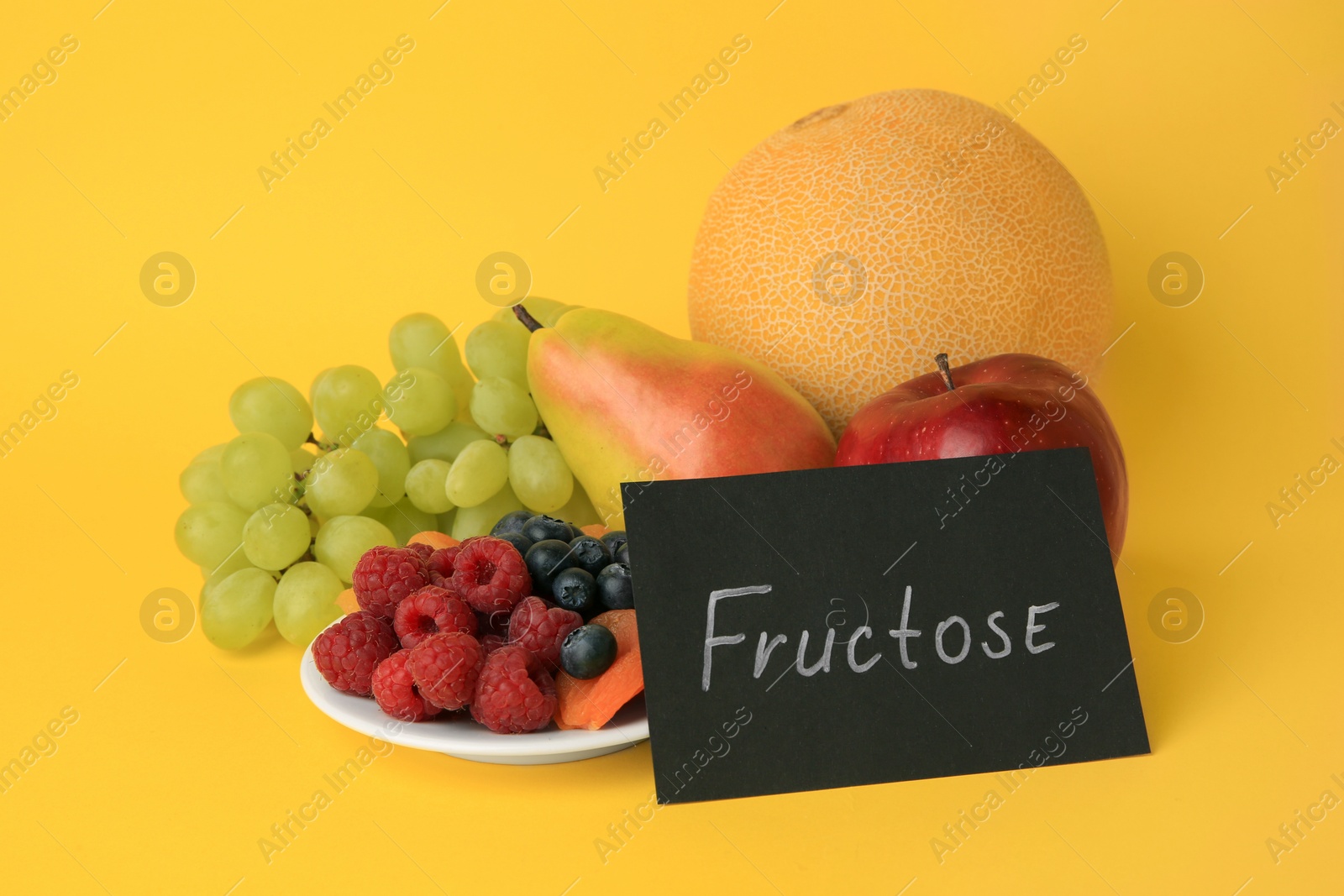 Photo of Card with word Fructose, delicious ripe fruits, berries and dried apricots on yellow background