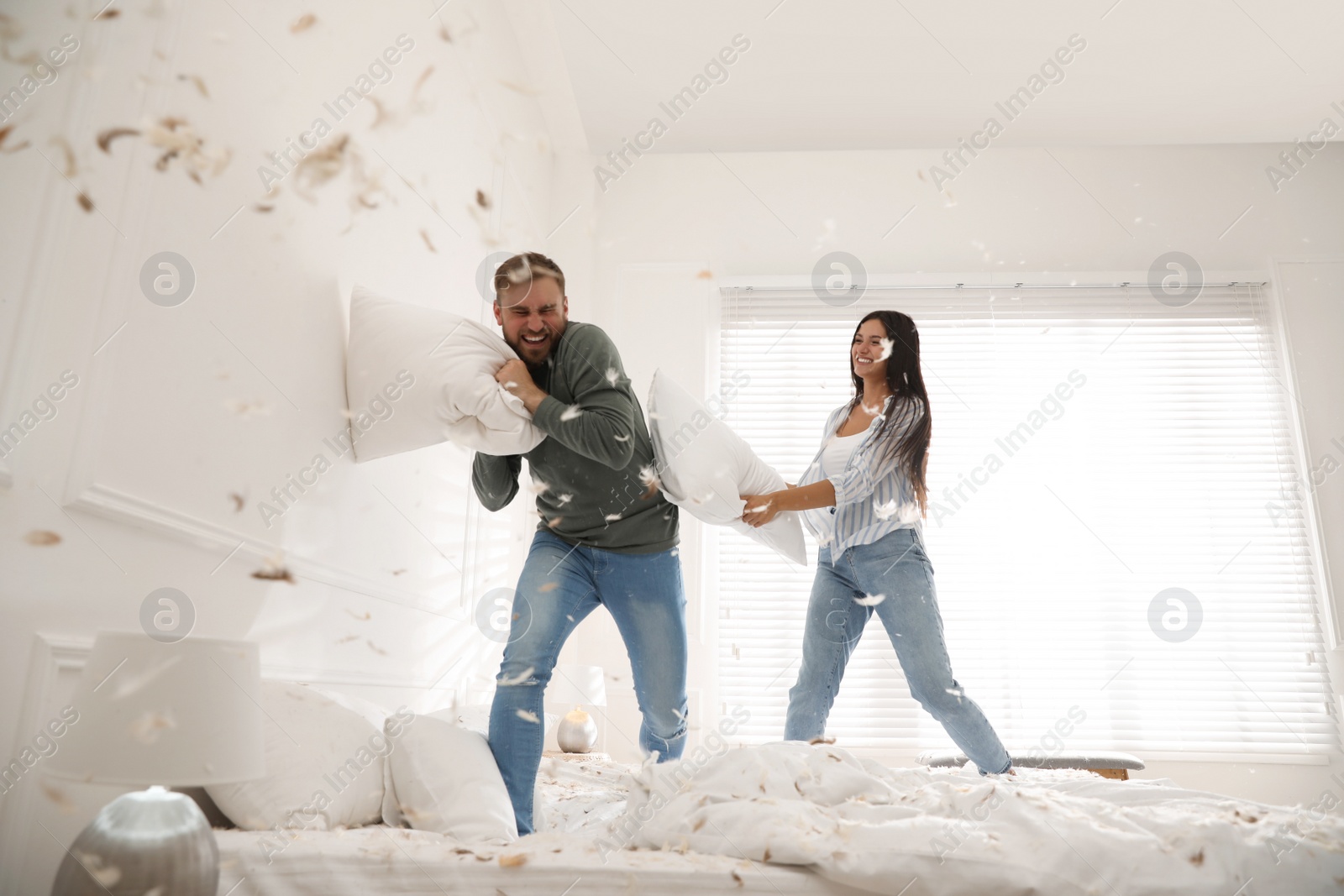 Photo of Happy young couple having fun pillow fight in bedroom