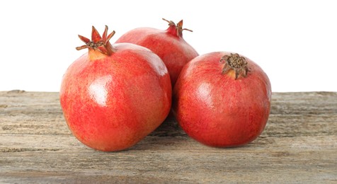 Fresh pomegranates on wooden table against white background