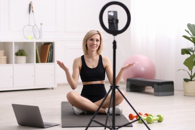 Photo of Smiling sports blogger streaming online fitness lesson at home