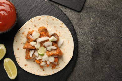 Photo of Delicious taco with vegetables, meat and ketchup on grey textured table, top view. Space for text