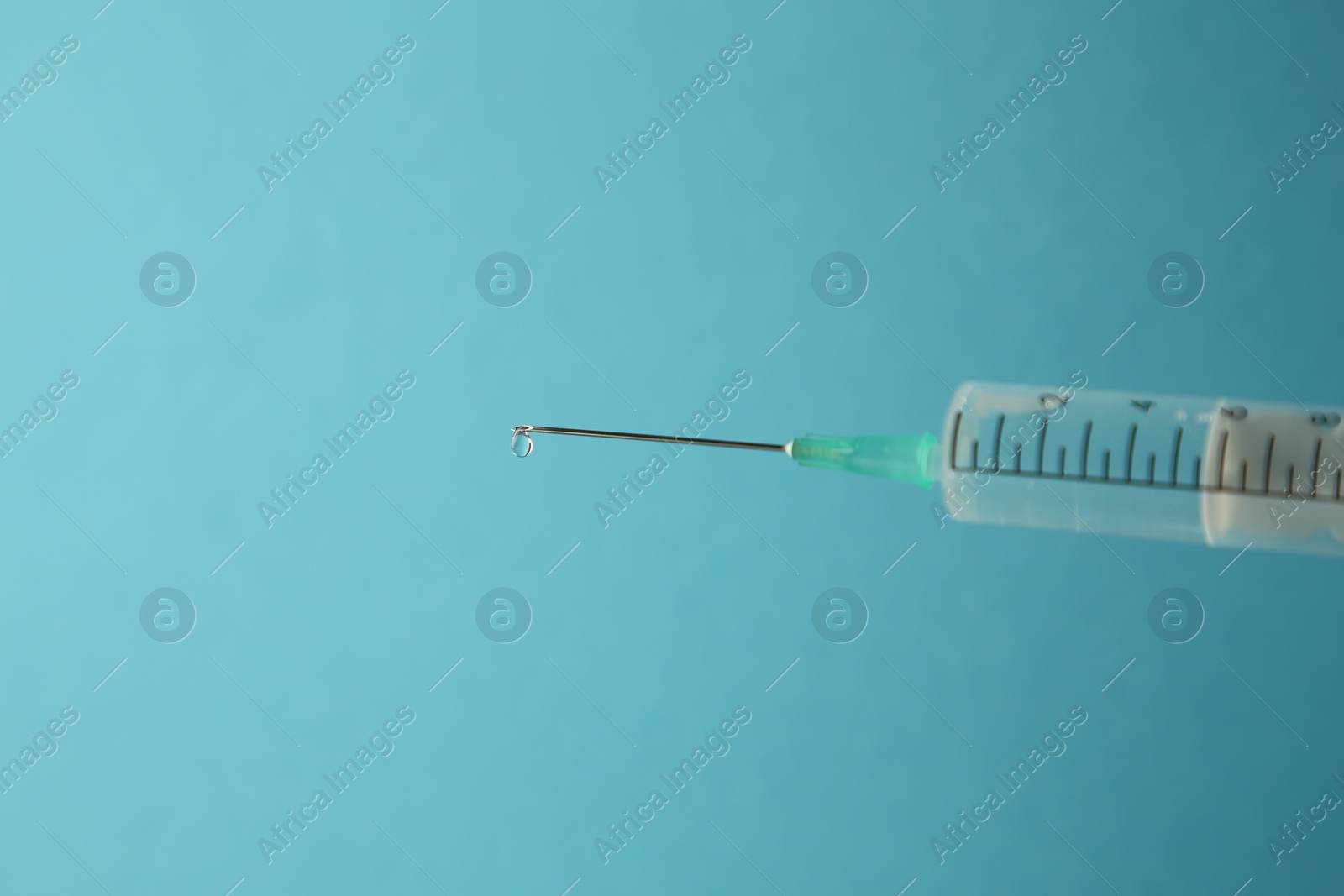 Photo of Medical syringe on light blue background, closeup. Space for text