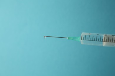 Medical syringe on light blue background, closeup. Space for text